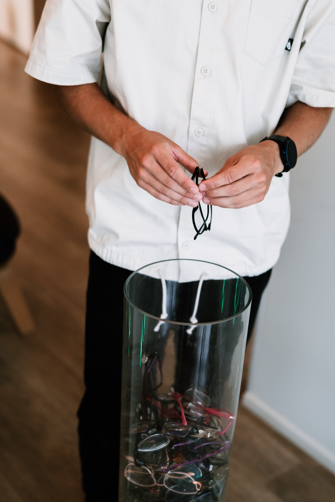 Inimene paneb prillid vaasi, mis on täis vanu prille — vabaduse hetk